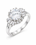 The Elian CZ Baguette Ring in polished silver-toned finish with a clear round center stone and baguette accents, front three-quarter product-only pearl-white studio view — reference-based AI visualization.
