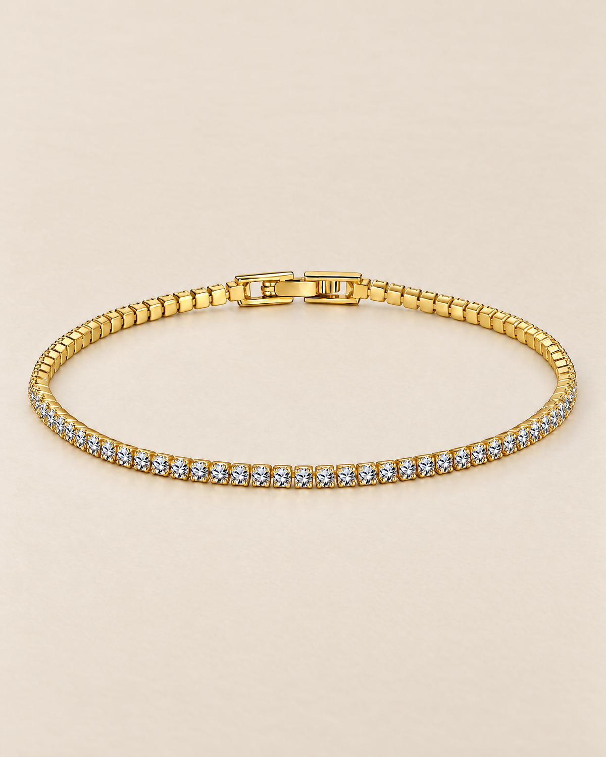 The Mila Tennis Bracelet in Gold Tone, shown as a full oval with clear stones and a closed clasp on a warm pale-greige studio background, reference-based AI visualization.