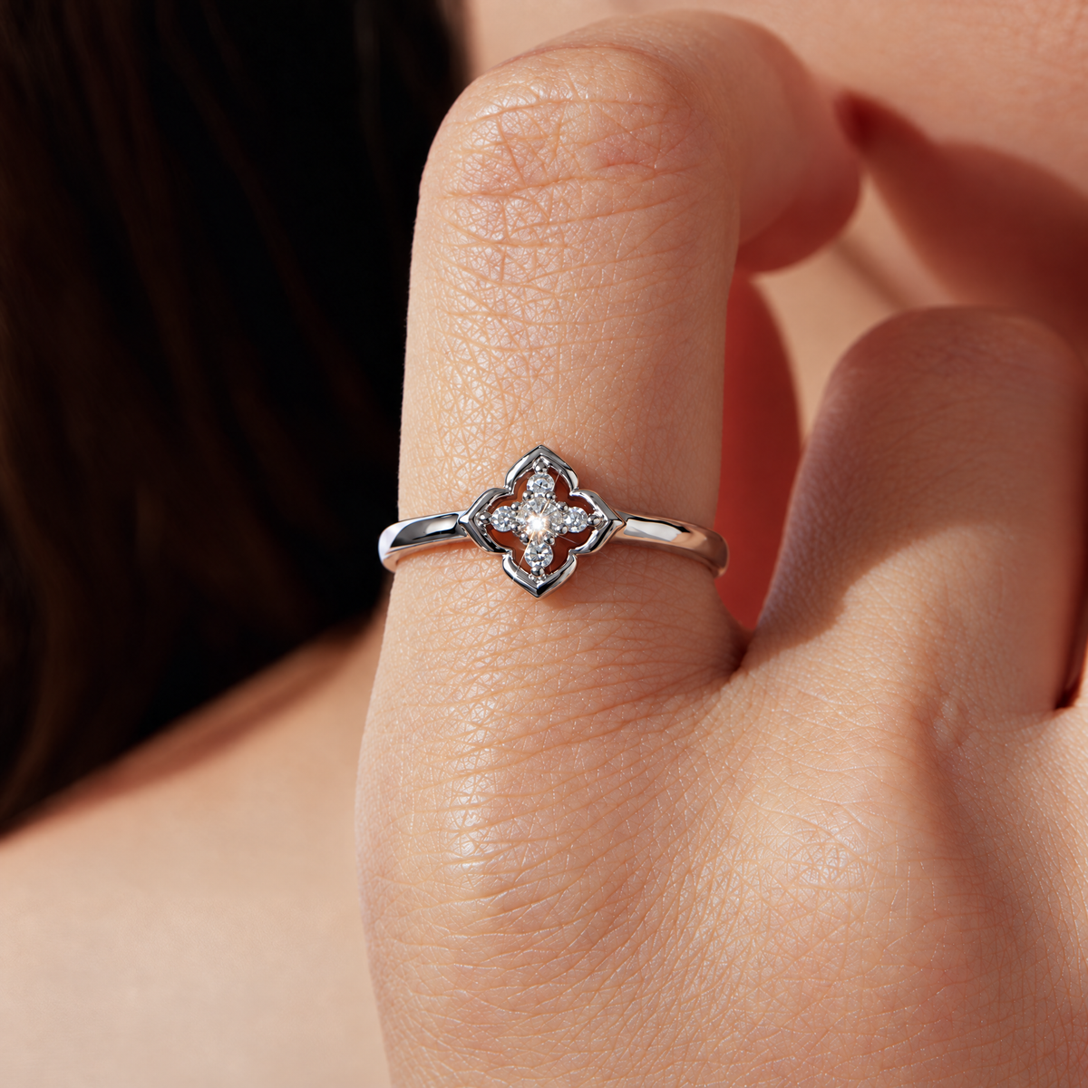 The Seren Quatrefoil Moissanite Ring in visible silver-tone finish, complete high-angle diagonal resting studio view on a pearl-white background, reference-based AI visualization.