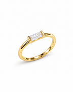 The Lyra CZ Emerald-Cut Statement Ring — gold-color complete diagonal product view with a clear emerald-cut center stone on a pearl-white studio background; reference-based AI visualization.