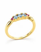 The Miri Color-Accent Band with a polished yellow-gold-colored band, three light-blue round stones and two magenta round accent stones, complete front three-quarter product-only view on a pearl-white studio background, reference-based AI visualization