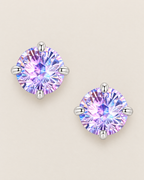 The Frida Firework CZ Stud Earrings: separated overhead pair of purple-lilac faceted round studs in four polished cool silver-tone prongs on pale greige, reference-based AI visualization