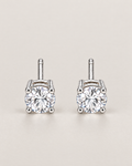 The Neva CZ Stud Earrings — silver-tone upright front pair with two clear round stones in a pale-greige studio; reference-based AI visualization.