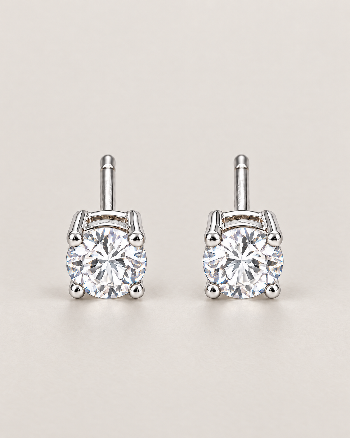 The Neva CZ Stud Earrings — silver-tone upright front pair with two clear round stones in a pale-greige studio; reference-based AI visualization.