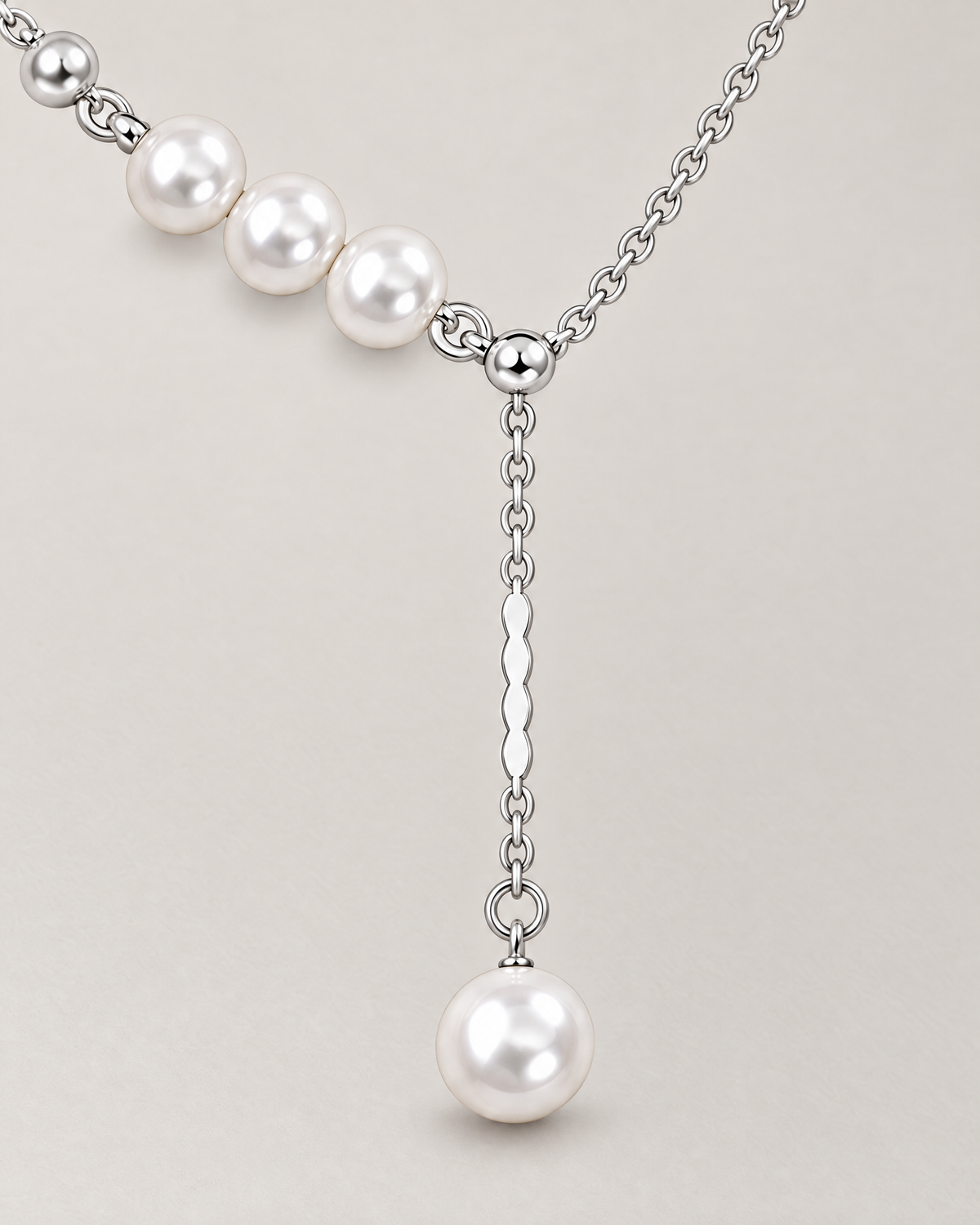 The Freya Pearl Drop Necklace — cool silver-color pearl-accented Y-drop detail on pale greige, reference-based AI visualization