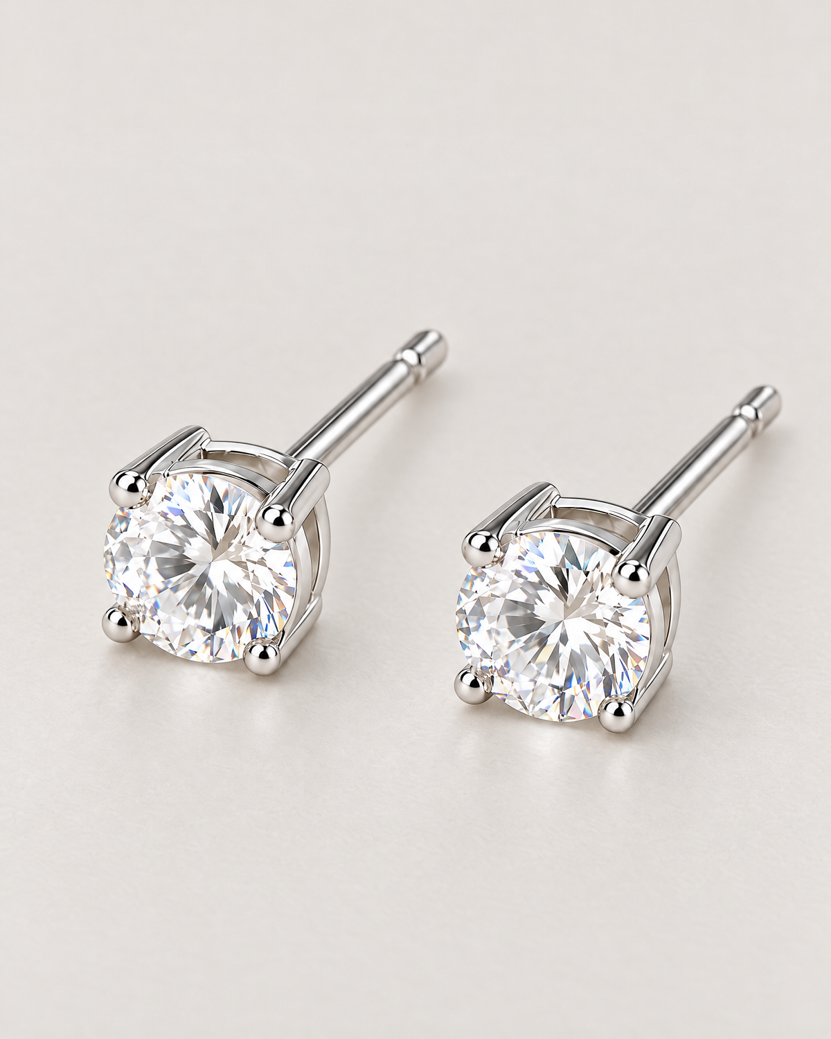 The Neva CZ Stud Earrings — closer silver-tone pair view with clear round stones, open settings, and posts in a pale-greige studio; reference-based AI visualization.