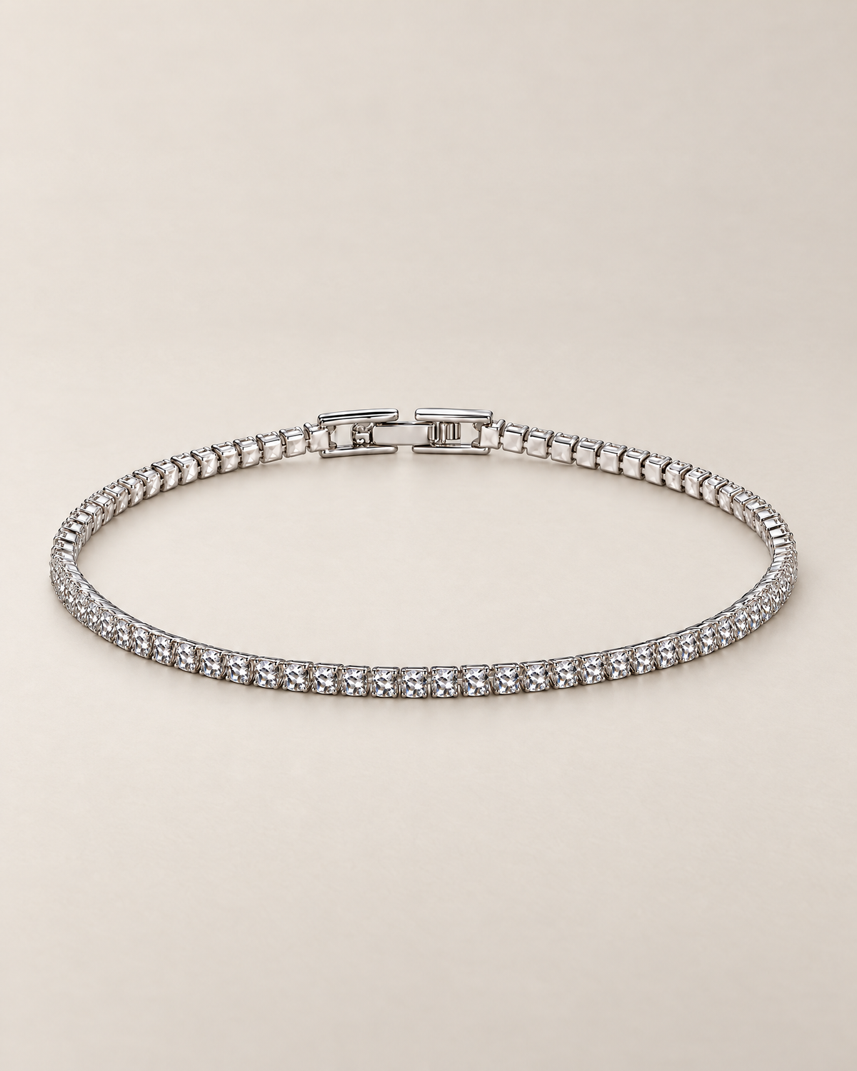 The Mila Tennis Bracelet in Silver Tone, shown as a full oval with clear stones and a closed clasp on a warm pale-greige studio background, reference-based AI visualization.
