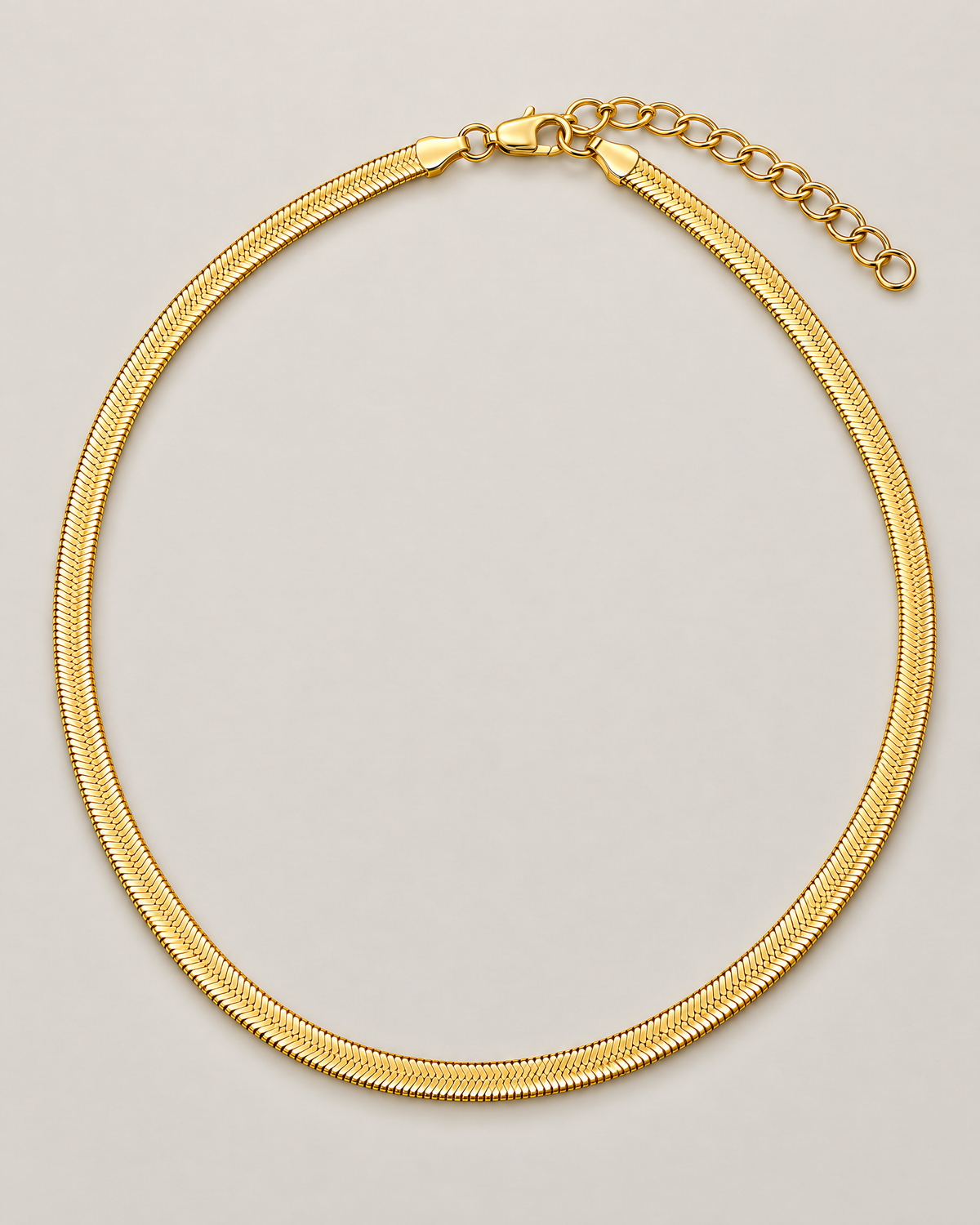 Gold-tone flat herringbone necklace in a tall rounded loop with closure and oval-link extender emphasized at the top on a pale greige studio ground; reference-based AI visualization