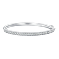 The Maia Pavé Hinge Bangle in polished silver-tone with a clear-stone pavé front band and compact hinge/catch on pale greige, reference-based AI visualization