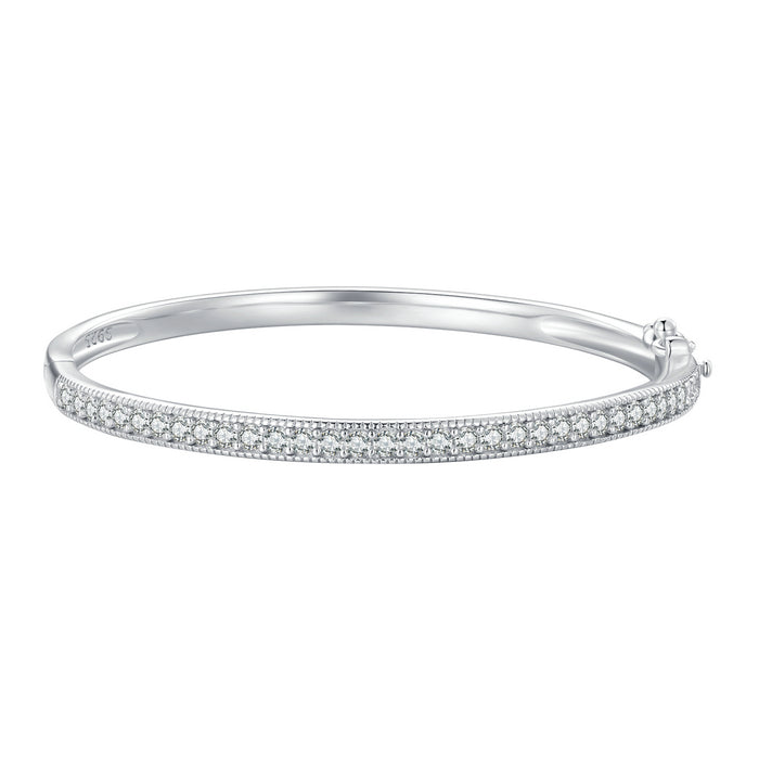 The Maia Pavé Hinge Bangle in polished silver-tone with a clear-stone pavé front band and compact hinge/catch on pale greige, reference-based AI visualization