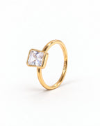 The gold-finish Eira Square Solitaire Ring shown complete from a left-facing three-quarter setting-profile angle on pearl white, with the source-observed S925 interior marking; reference-based AI visualization.