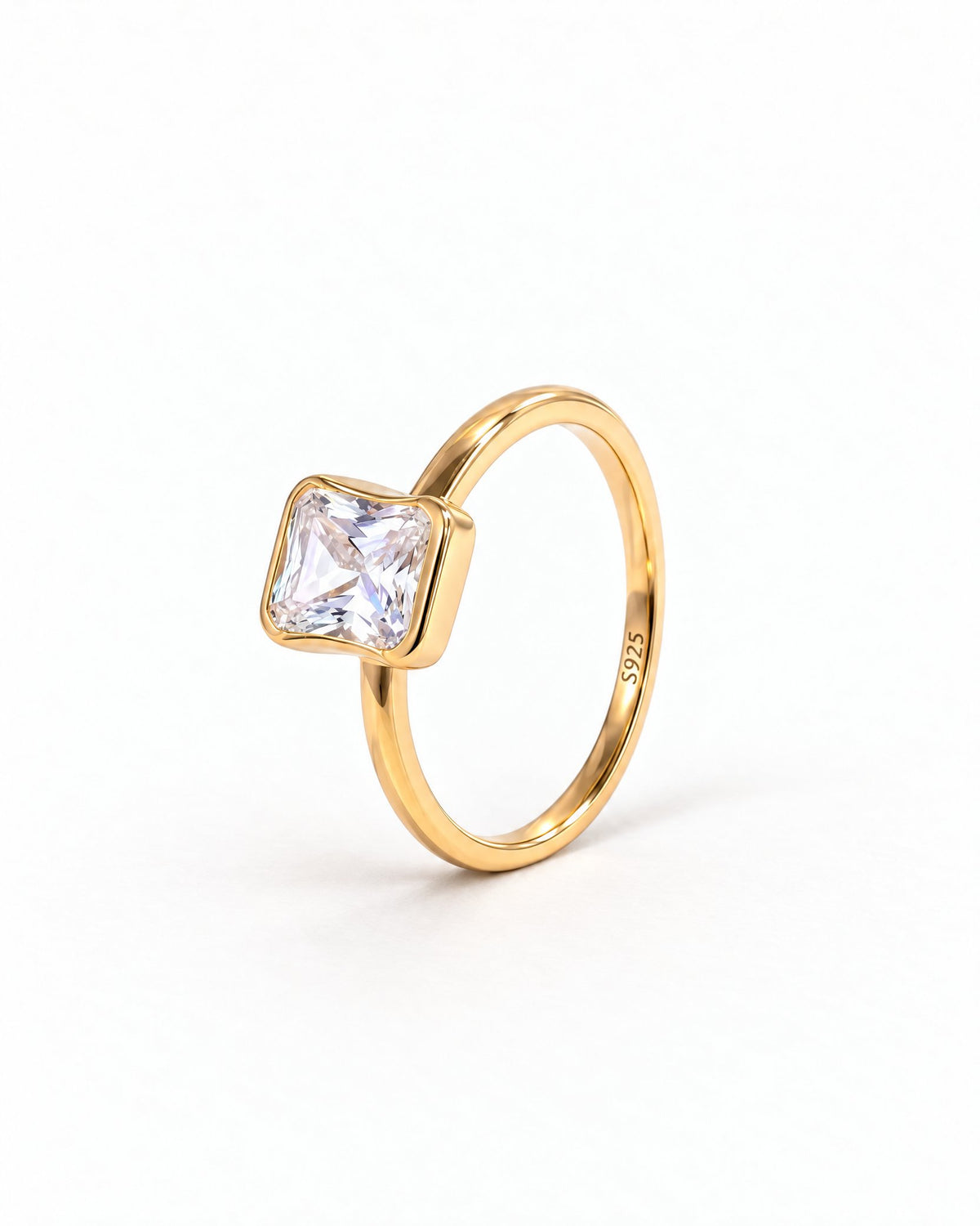 The gold-finish Eira Square Solitaire Ring shown complete from a left-facing three-quarter setting-profile angle on pearl white, with the source-observed S925 interior marking; reference-based AI visualization.