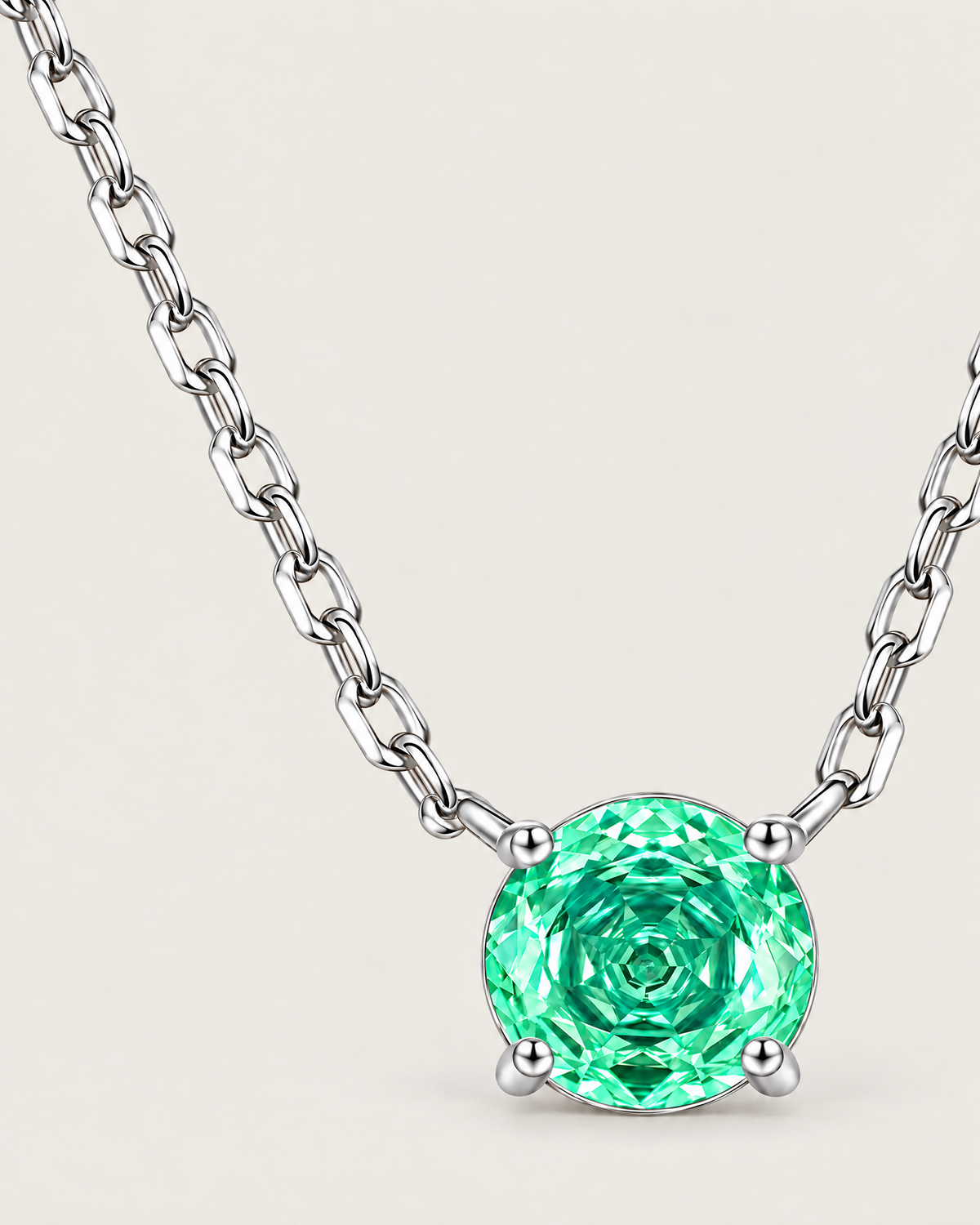 Round green faceted pendant in a silver-colored four-prong setting placed off-center with an asymmetrical linked-chain sweep on pale greige — reference-based AI visualization