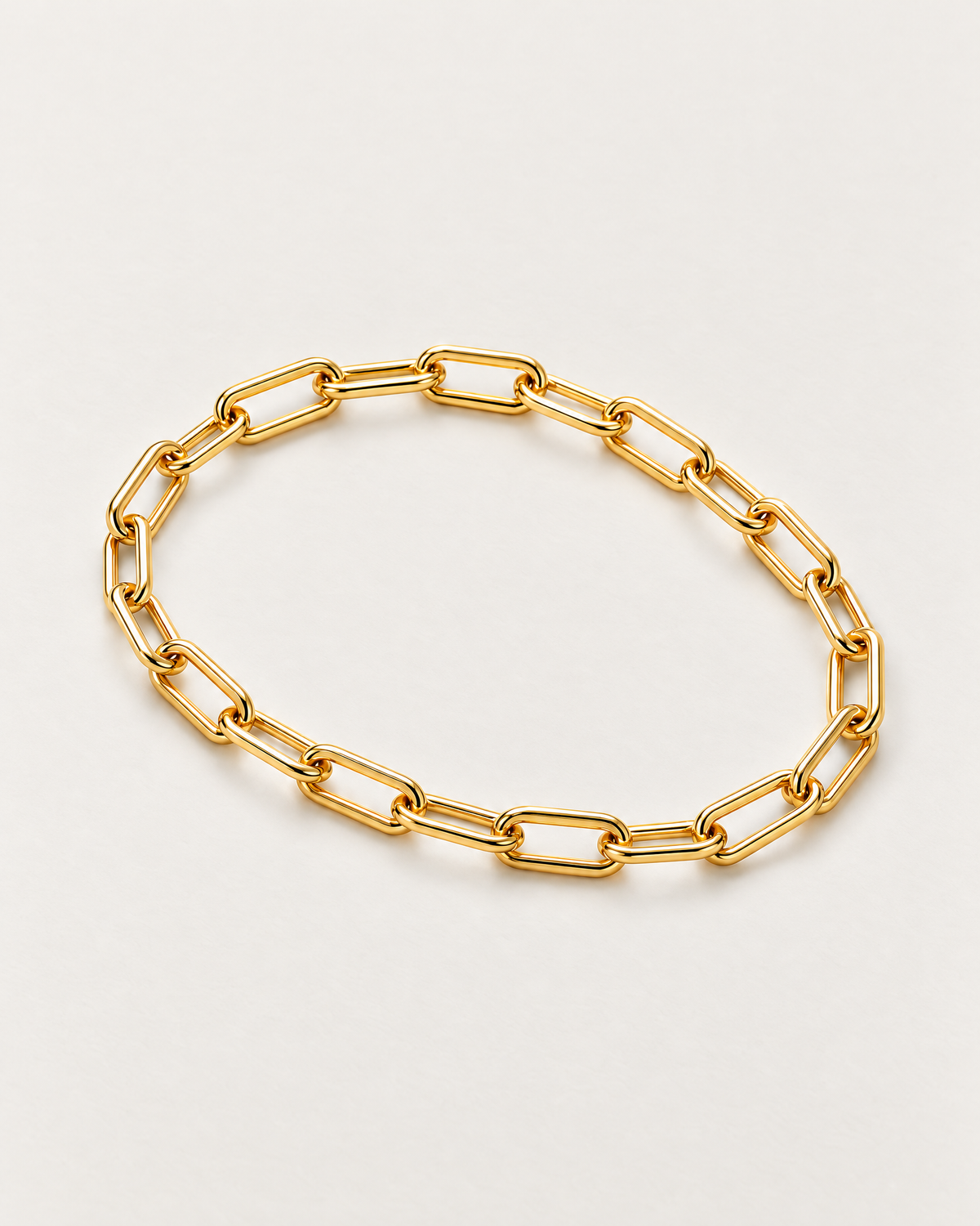 The Linnea Link Bracelet — polished gold-color paperclip-link overhead resting lay on pale greige — reference-based AI visualization