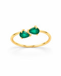 The Tove Green Twin-Pear Ring in polished yellow-gold coloured metal with two green pear-cut stones, upright front three-quarter product-only view on a pearl-white studio background, reference-based AI visualization.