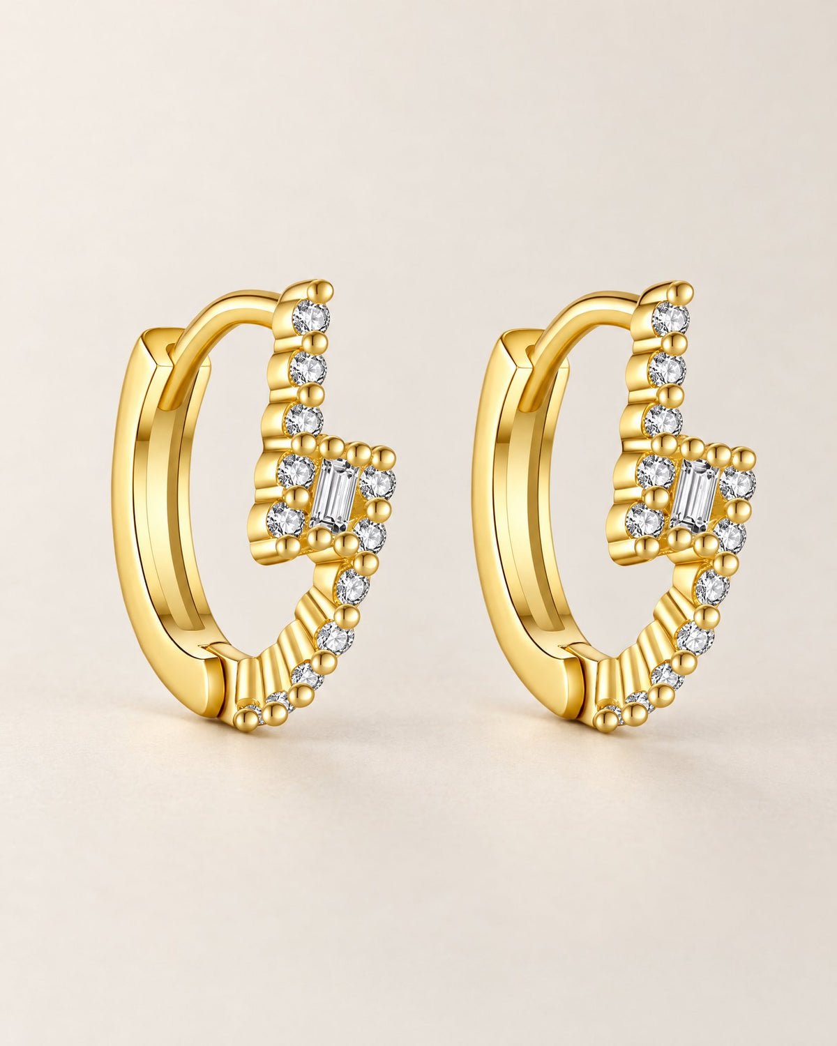 The Veyra Geometric Huggies, paired upright warm yellow-gold-coloured geometric huggies with clear rectangular and round stones on pale greige, reference-based AI visualization