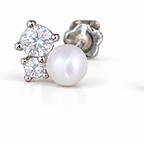 The Elva Pearl & Moissanite Stud Earrings, single silvery stud macro with a luminous white pearl and two clear round stones on pale greige, reference-based AI visualization.