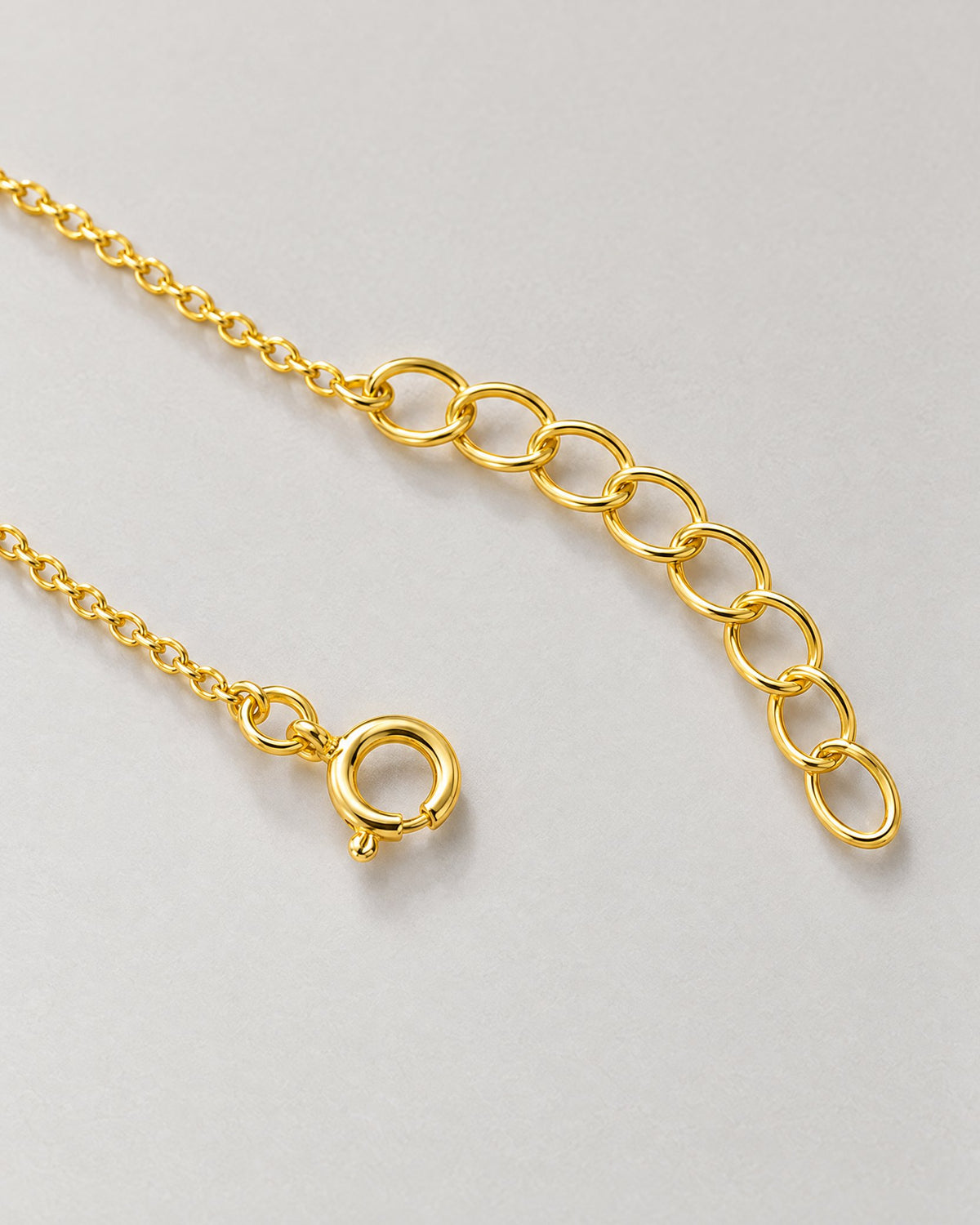 The Amelie Pearl Station Bracelet with its polished yellow-gold-tone spring-ring closure, fine chain and oval extension links on pale greige, reference-based AI visualization