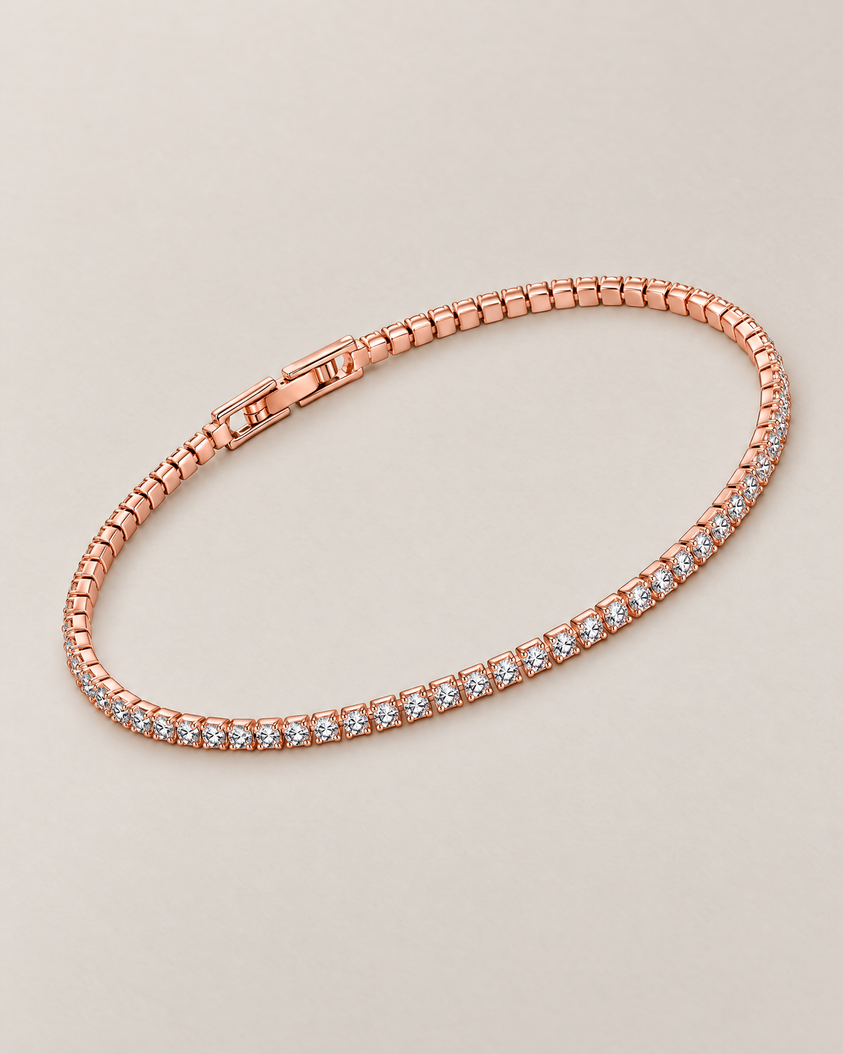 The Mila Tennis Bracelet in Rose Gold Tone, shown in a complete diagonal oval lay with clear stones and a closed clasp on a warm pale-greige studio background, reference-based AI visualization.