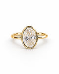 The Esme Bezel-Set Oval Ring in Gold Tone, complete front three-quarter product-only hero on a pearl-white studio background, reference-based AI visualization.