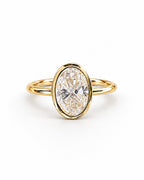 The Esme Bezel-Set Oval Ring in Gold Tone, complete front three-quarter product-only hero on a pearl-white studio background, reference-based AI visualization.