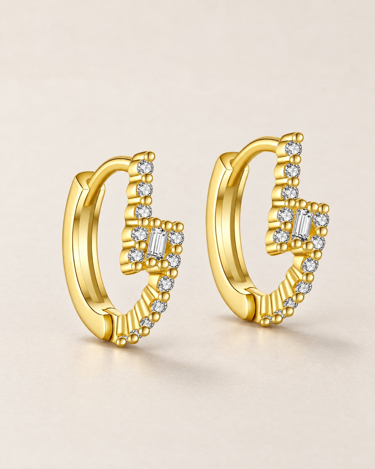 The Veyra Geometric Huggies, gently staggered warm yellow-gold-coloured geometric huggies with clear rectangular and round stones on pale greige, reference-based AI visualization