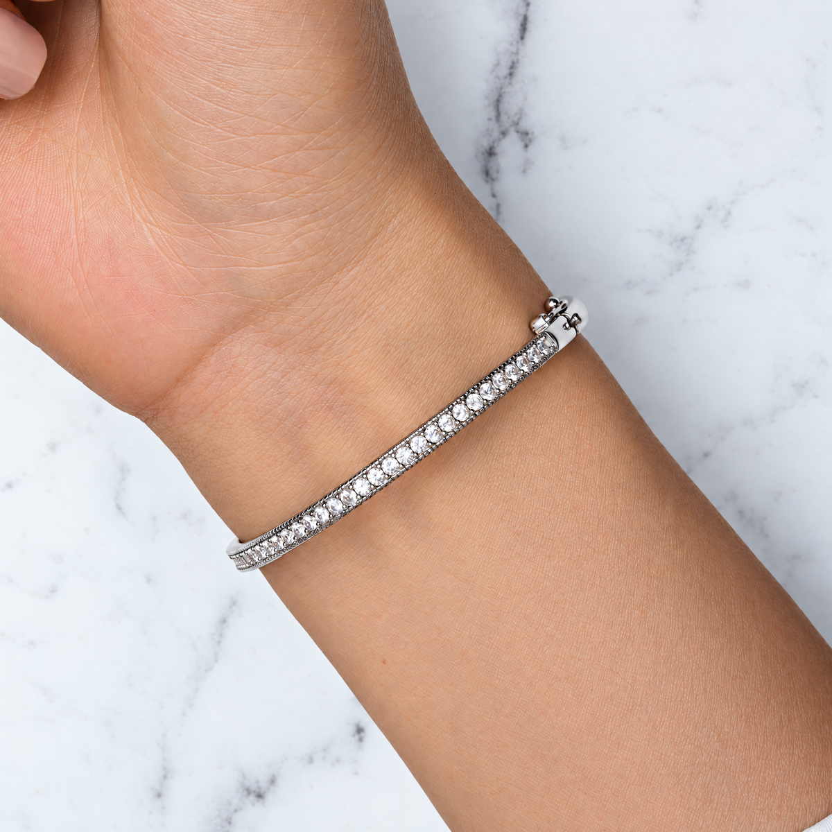 The Maia Pavé Hinge Bangle polished silver-tone pavé-panel detail with clear stones and beaded edges on pale greige, reference-based AI visualization
