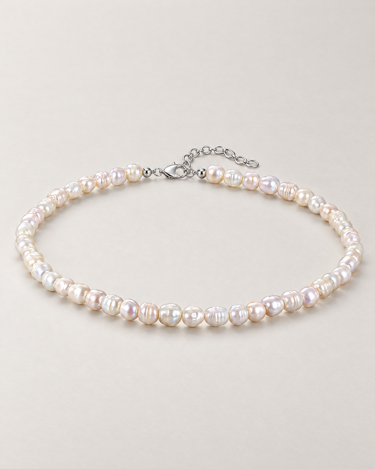Irregular off-white pearl strand in a complete low oblique oval with visible clasp and extension on a pale greige studio surface; reference-based AI visualization