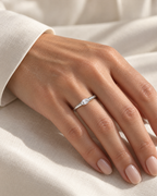 The Aure Marquise-Cut CZ Ring, polished silver marquise-cut ring worn on a light-warm adult hand with ivory linen in warm window light — reference-based AI visualization.