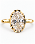 The Esme Bezel-Set Oval Ring in Gold Tone, oval stone and smooth bezel macro on a pearl-white studio background, reference-based AI visualization.
