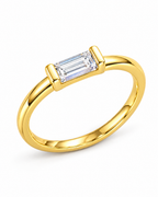 The Lyra CZ Emerald-Cut Statement Ring — gold-color closer emerald-cut center and end-bar-prong detail on a pearl-white studio background; reference-based AI visualization.