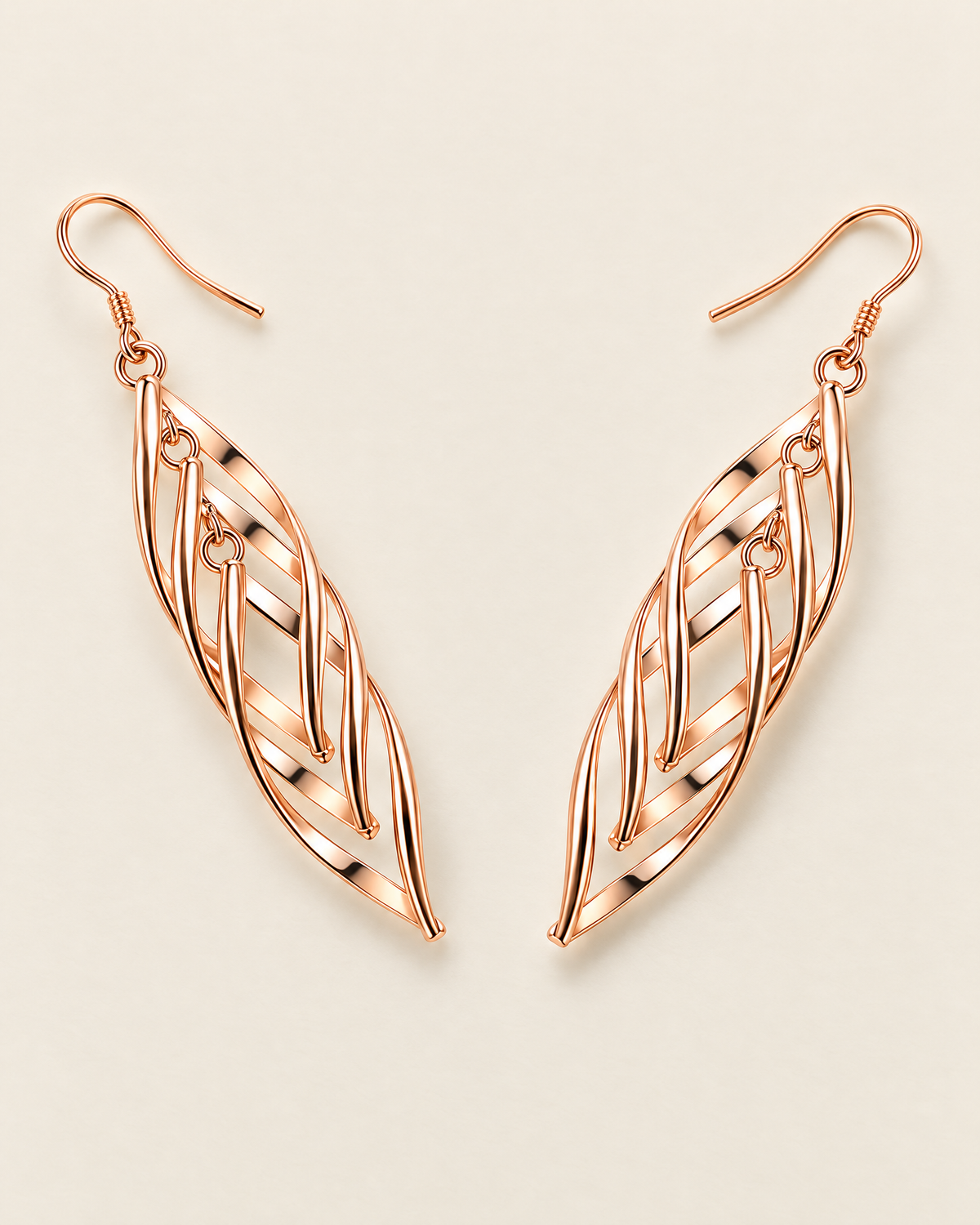 The Sova CZ Drop Earrings — Warm gold-color openwork leaf drop pair in a wide V overhead lay on pale greige; reference-based AI visualization