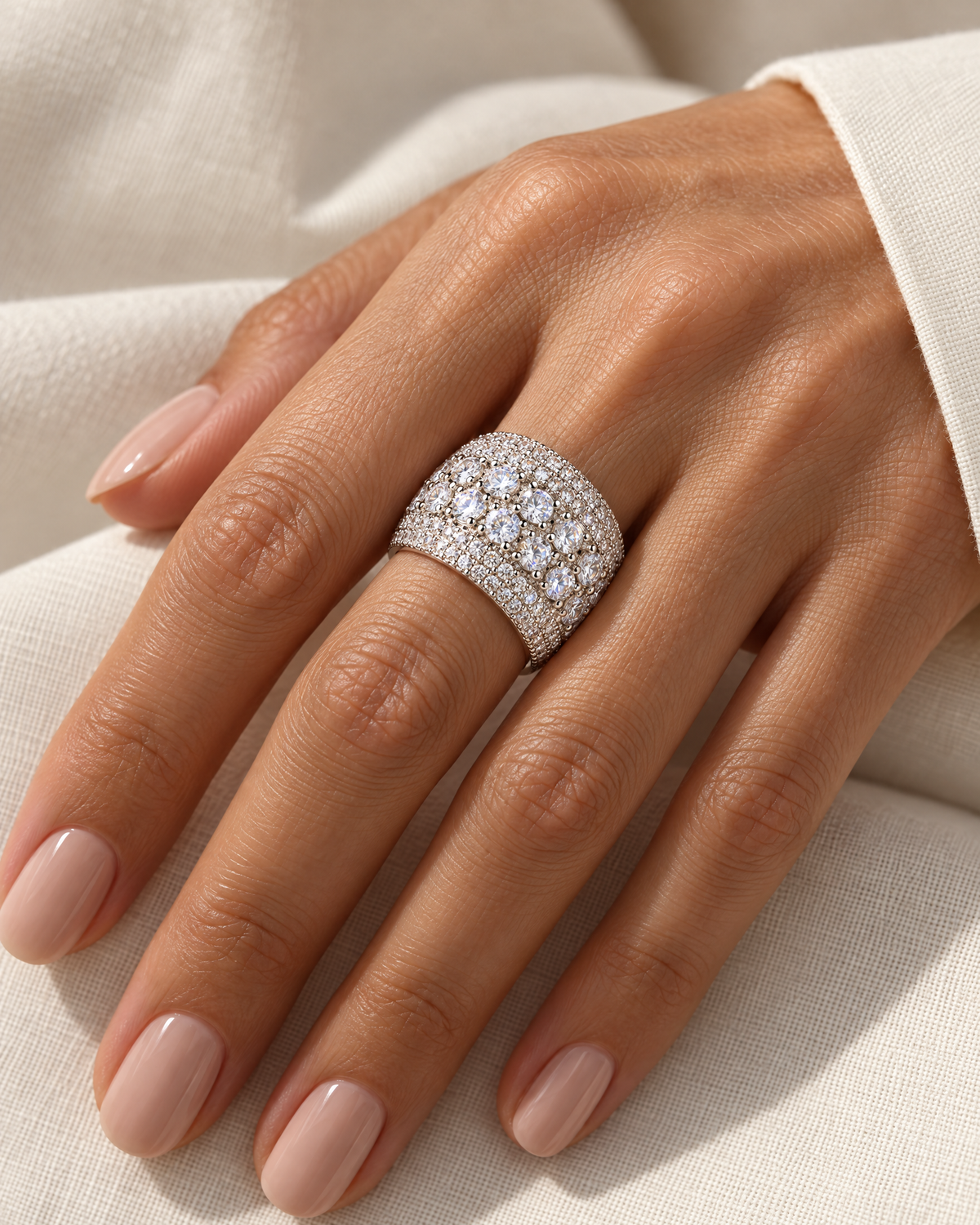 The Solis CZ Dome Ring — silver-color pavé dome ring correctly worn on a natural adult hand with ivory linen, reference-based AI visualization.