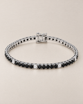 The Signe Black & White CZ Tennis Bracelet in polished silver-tone metal, shown as a full oval with repeating black and clear/white round stones and a box clasp on pale greige, reference-based AI visualization.