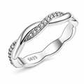 The Veda CZ Twisted Band — polished silver twisted band with clear round CZ accents, front three-quarter product-only hero on pearl-white studio background; reference-based AI visualization.