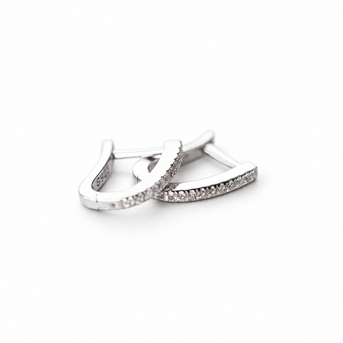 The Aria CZ Hoops — overlapping polished silver-colored U-shaped hoops with clear round stone rows on pale greige, reference-based AI visualization