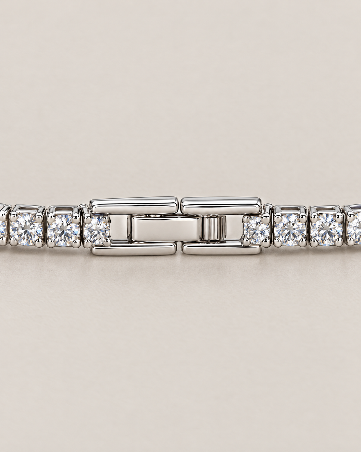 The Mila Tennis Bracelet in Silver Tone, shown as a macro detail of the closed clasp and adjacent clear-stone links on a warm pale-greige studio background, reference-based AI visualization.