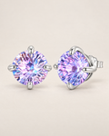 The Frida Firework CZ Stud Earrings: purple-lilac faceted round stud pair in four polished cool silver-tone prongs, front and three-quarter hero on pale greige, reference-based AI visualization