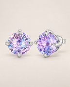 The Frida Firework CZ Stud Earrings: purple-lilac faceted round stud pair in four polished cool silver-tone prongs, front and three-quarter hero on pale greige, reference-based AI visualization