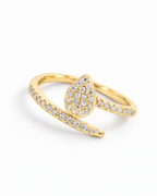The Oona Pavé Teardrop Ring in warm polished gold with clear round pavé stones, complete high-angle diagonal resting view on a pearl-white studio background; reference-based AI visualization.
