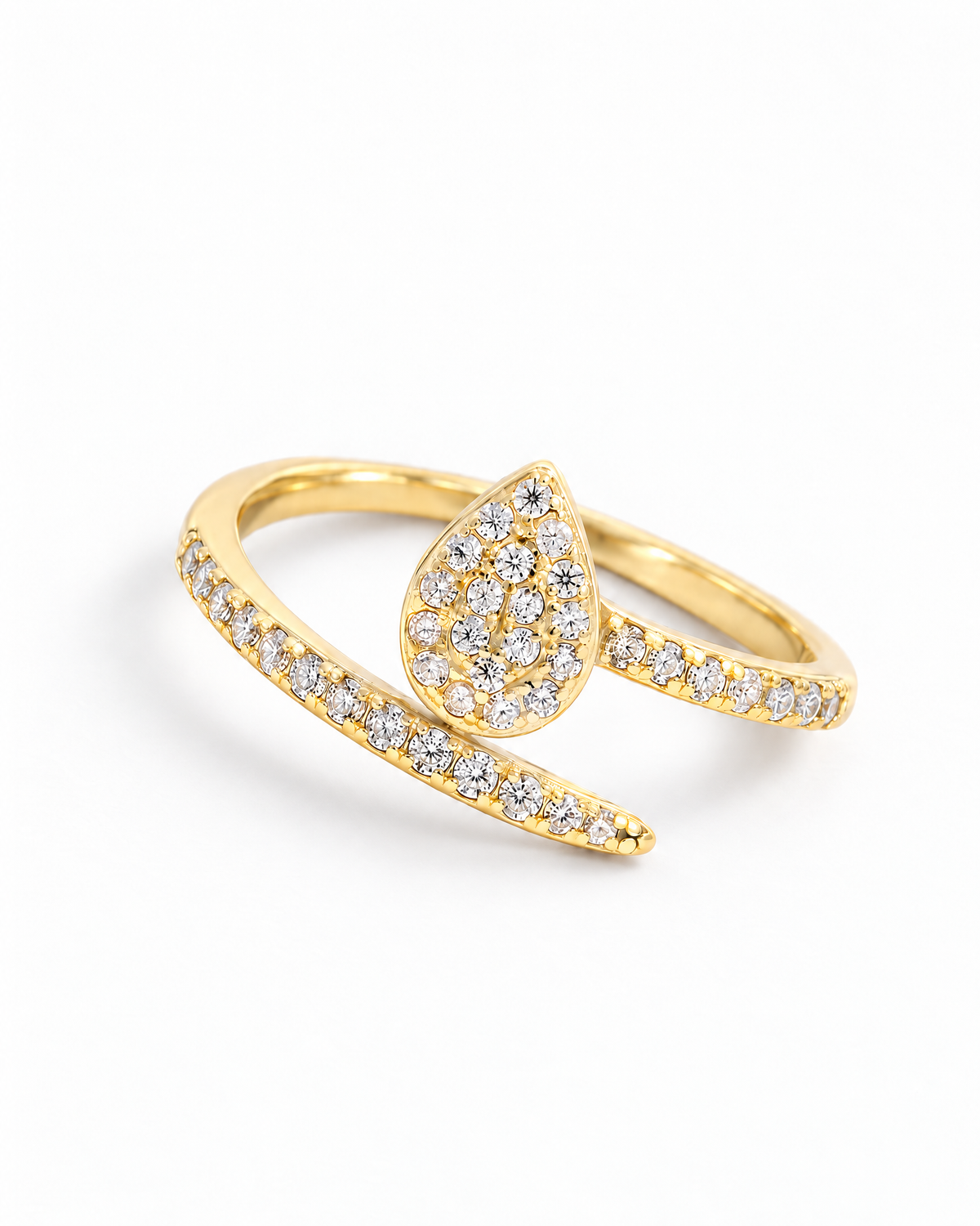 The Oona Pavé Teardrop Ring in warm polished gold with clear round pavé stones, complete high-angle diagonal resting view on a pearl-white studio background; reference-based AI visualization.