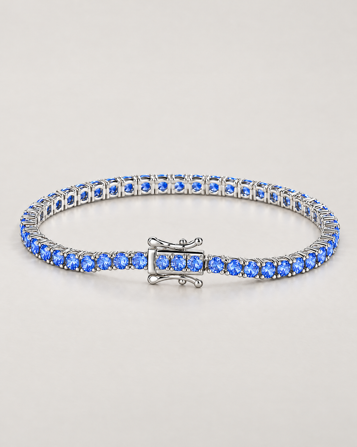 The Orla CZ Tennis Bracelet — polished silver-tone blue-stone tennis bracelet in a complete three-quarter oval on pale greige — reference-based AI visualization