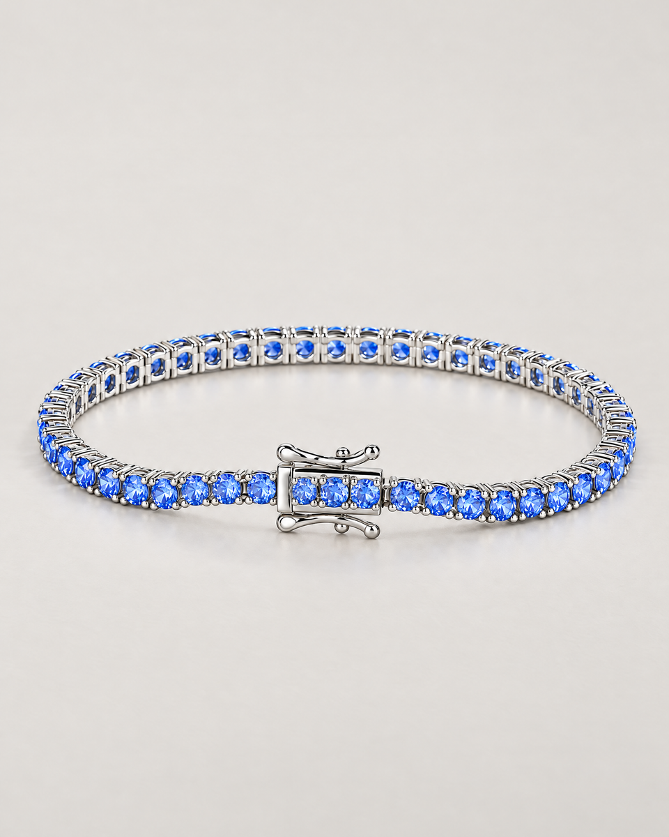 The Orla CZ Tennis Bracelet — polished silver-tone blue-stone tennis bracelet in a complete three-quarter oval on pale greige — reference-based AI visualization