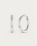 The Kiri Huggie Hoops — upright silver pair, front/edge-on and three-quarter views on pale greige; reference-based AI visualization.