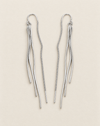 The Neri Threader Earrings, paired bright silver-tone mirrored tassel threaders on pale greige, reference-based AI visualization