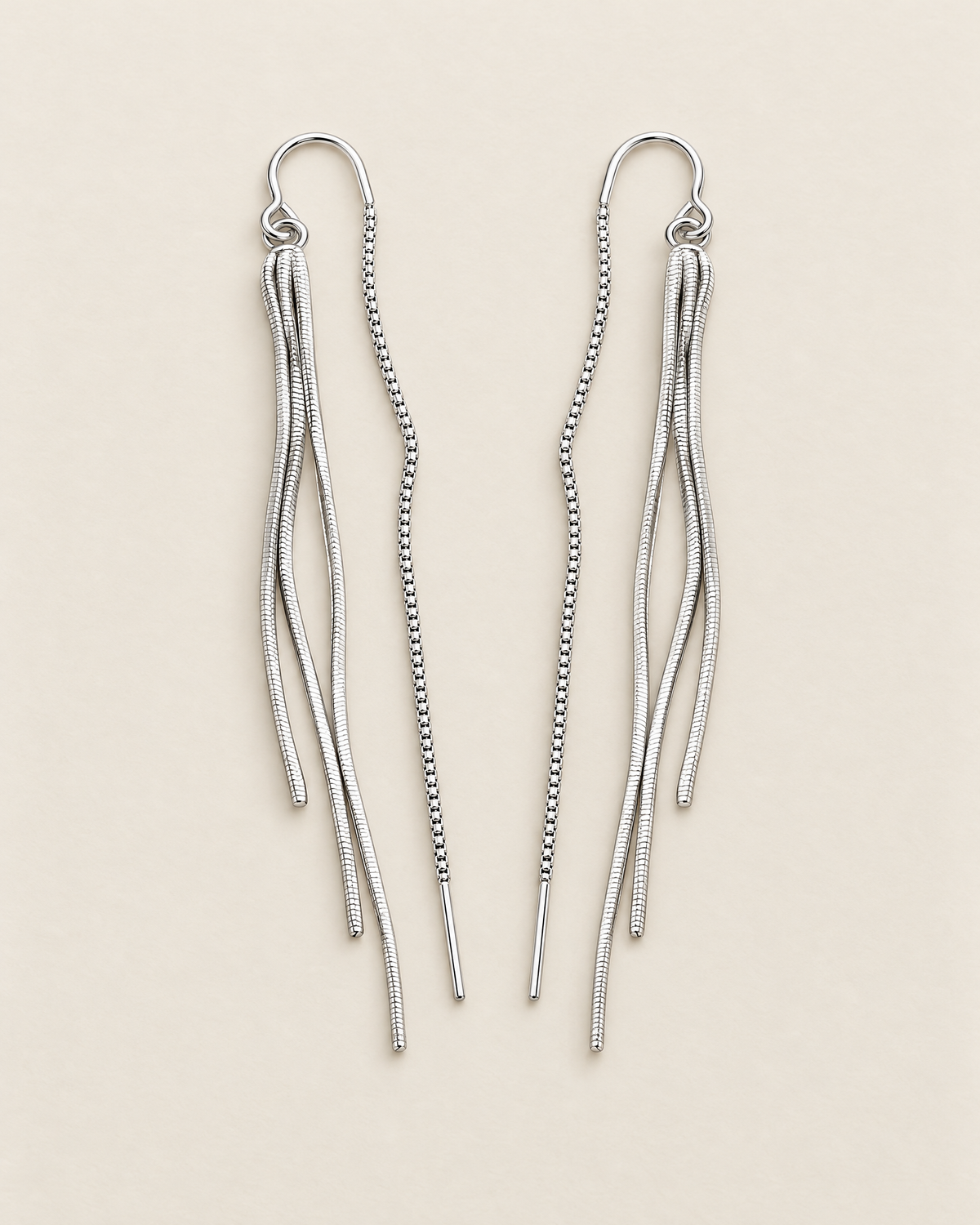 The Neri Threader Earrings, paired bright silver-tone mirrored tassel threaders on pale greige, reference-based AI visualization