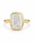 The Tilde Bezel Ring in polished yellow-gold tone with one clear faceted rounded-rectangle stone in an upright product-only pearl-white studio hero — reference-based AI visualization