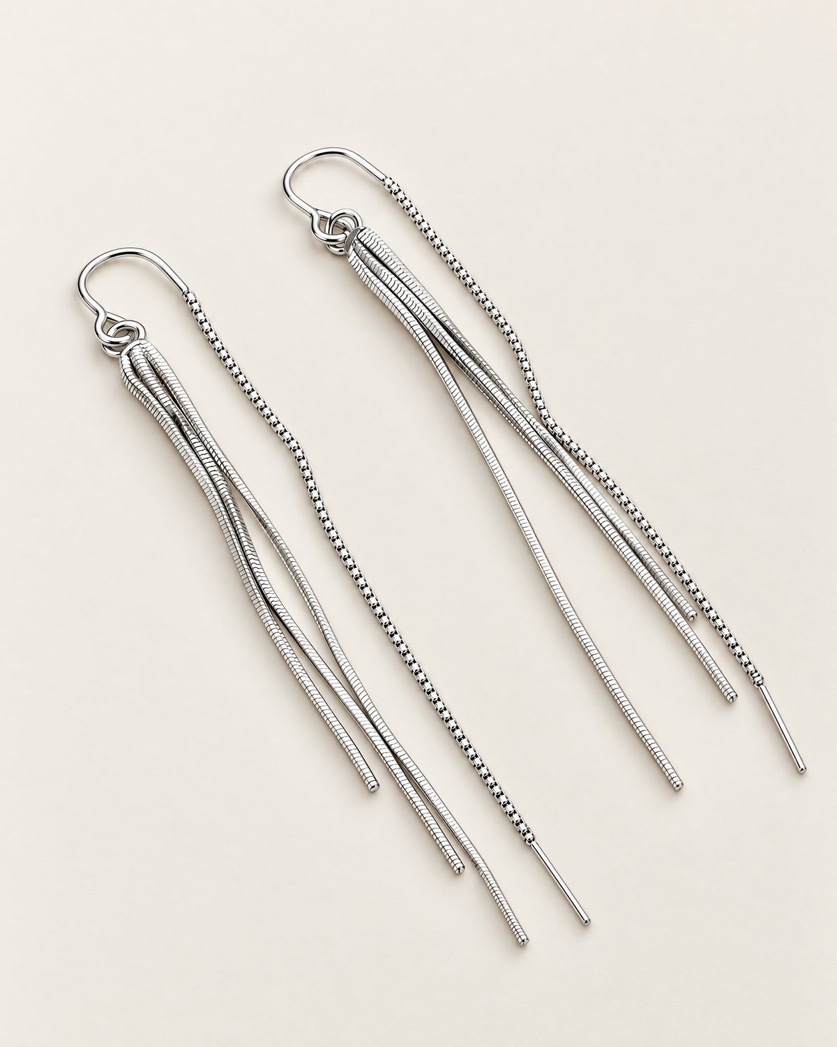 The Neri Threader Earrings, paired bright silver-tone open-wire threaders with textured tassels on pale greige, reference-based AI visualization