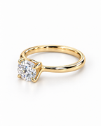 The Astrea Moissanite Solitaire Ring — warm gold-color low resting gallery view on a pearl-white studio background; reference-based AI visualization.