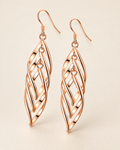 The Sova CZ Drop Earrings — Warm gold-color openwork leaf drop pair in a front three-quarter studio view on pale greige; reference-based AI visualization